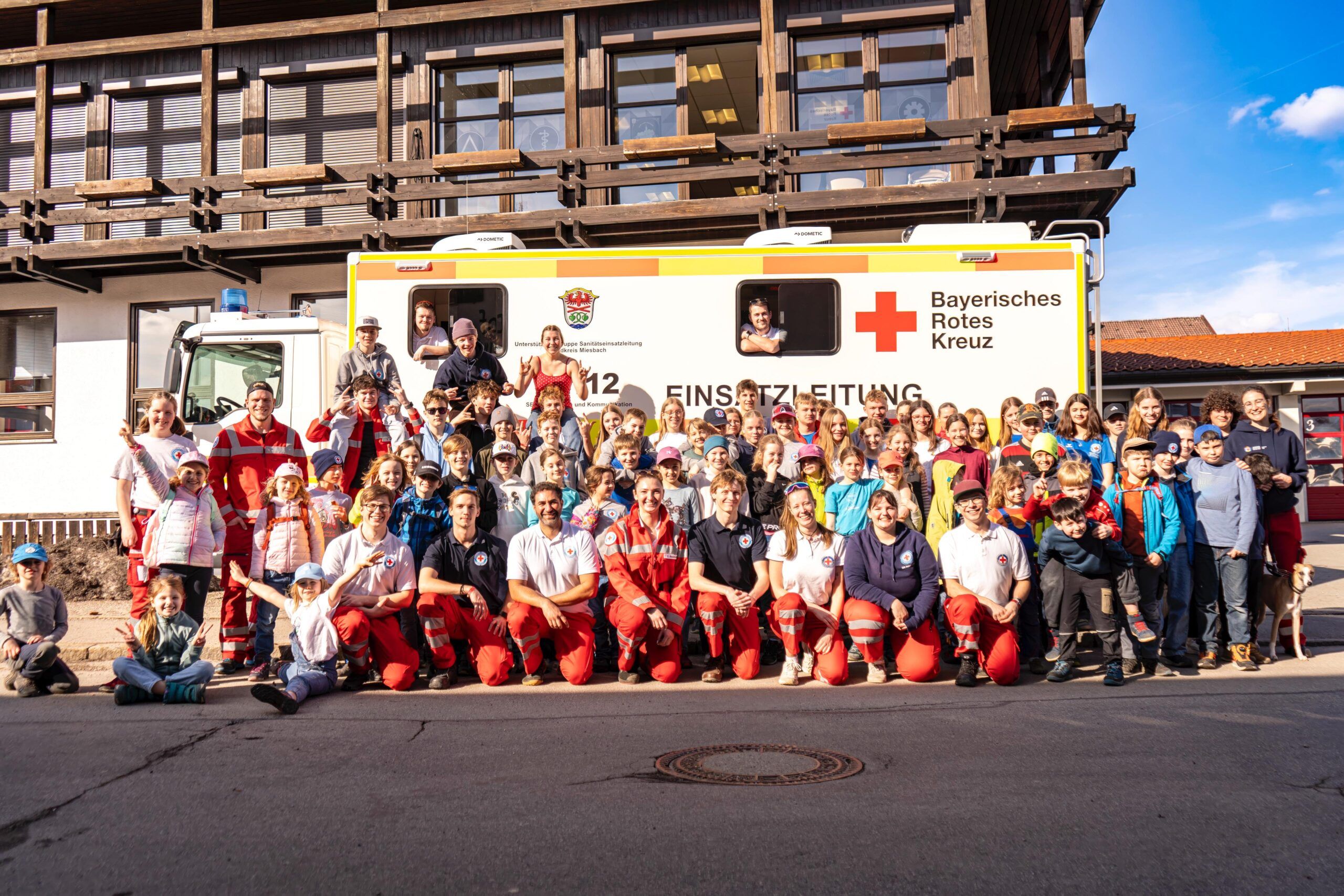 Kinder und Jugendliche der Wasserwachten im Landkreis Miesbach, unter anderem Schliersee, posieren vor dem Fahrzeug der Einsatzleitung nach erfolgreicher Durchführung einer gemeinsamen Funkübung