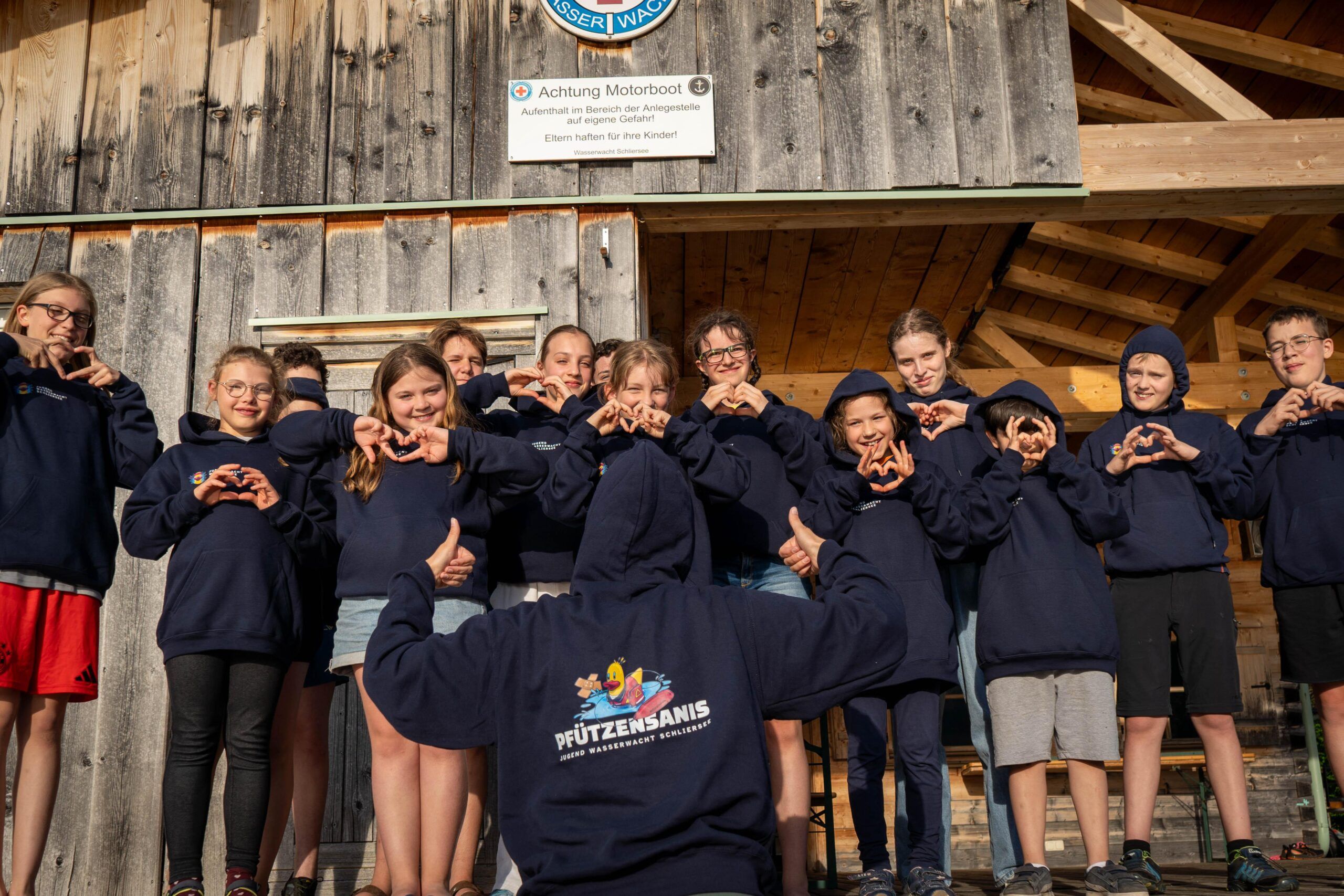 Jugendmitglieder präsentieren die neuen dunkelblauen Sweatshirts mit dem Aufdruck "Pfützensanis"