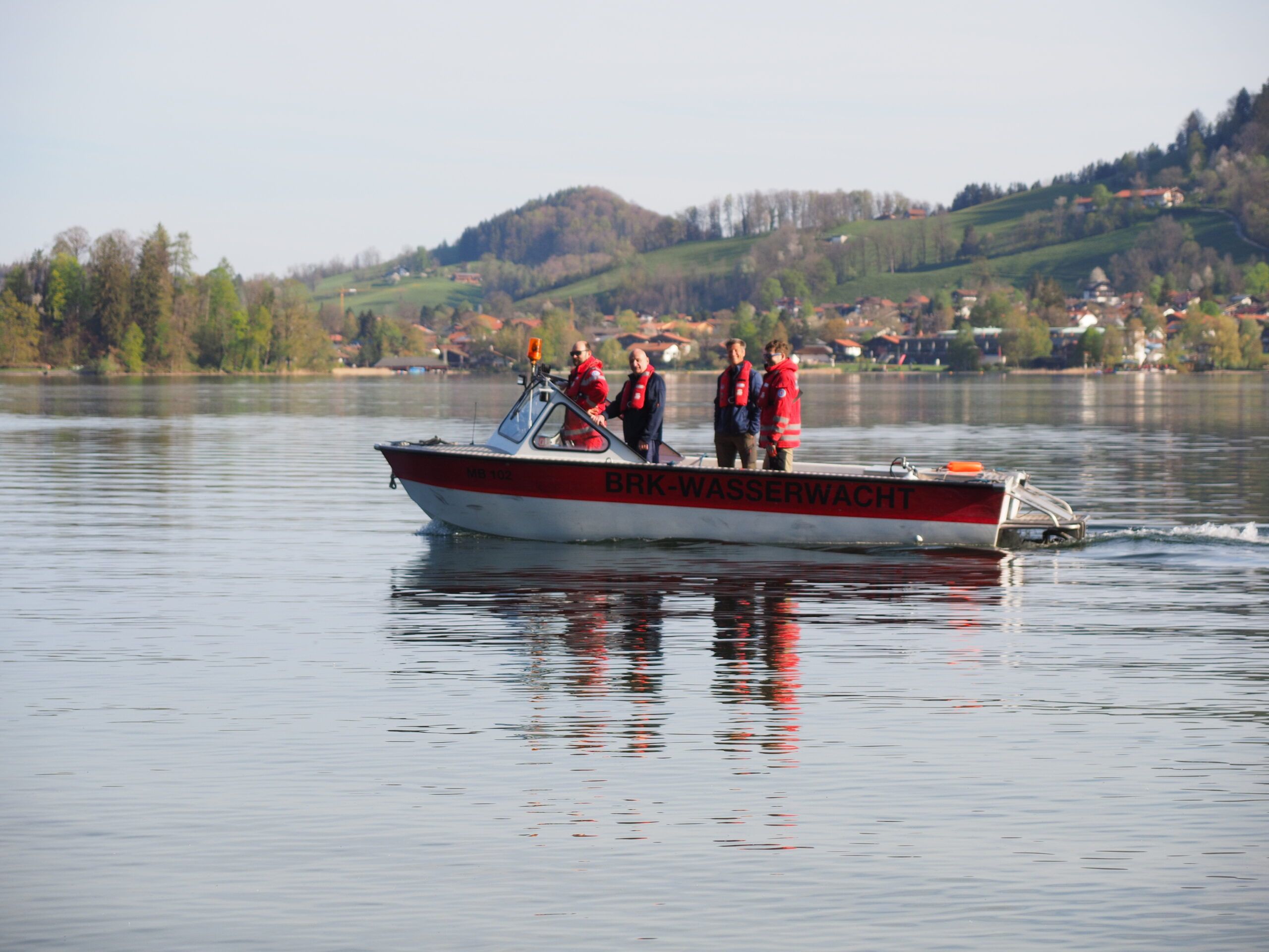 Rettungsboot fährt über den Schliersee um die Helfer zur Seeuferreinigung an das andere Ufer zu bringen