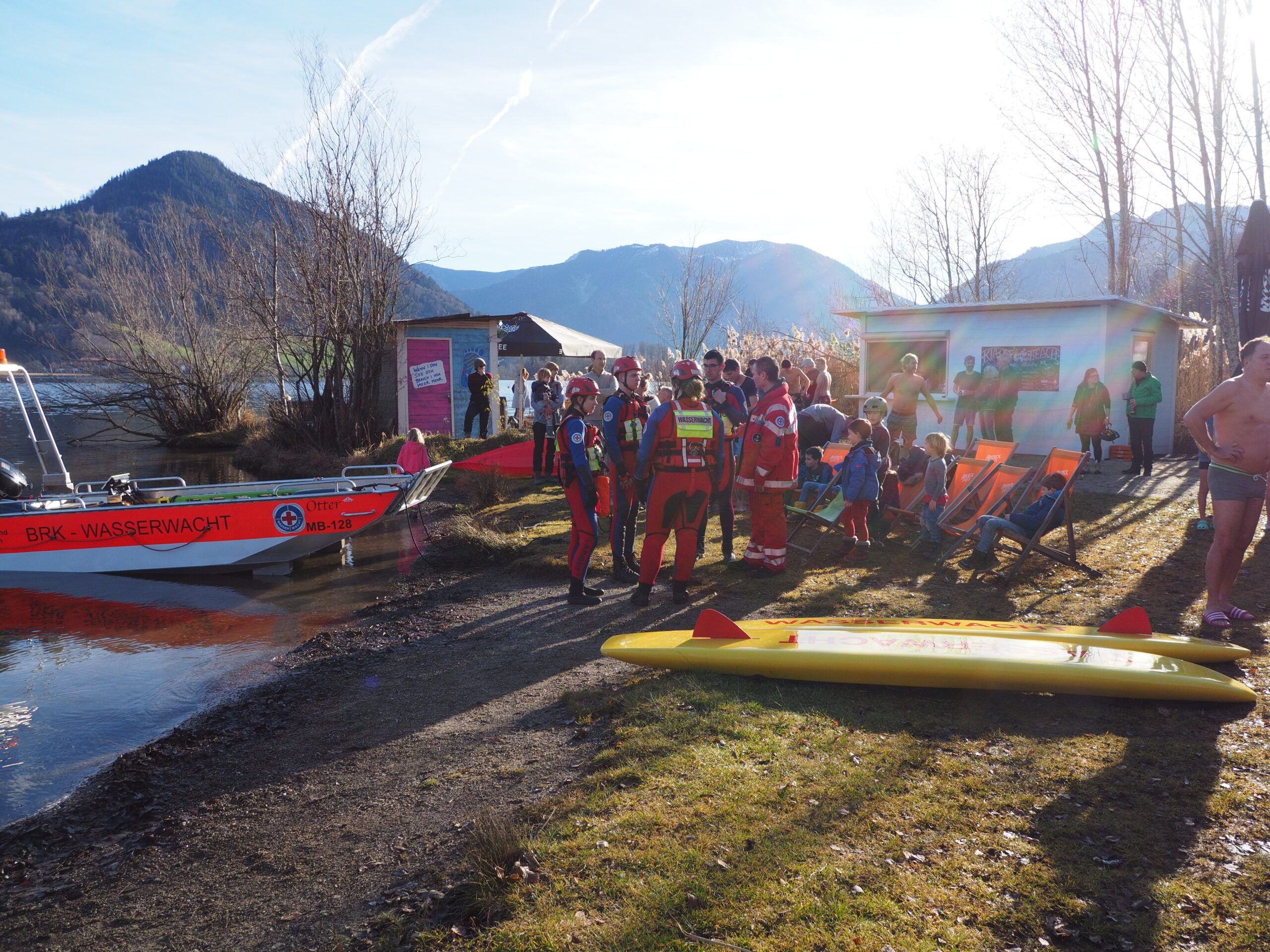 Der Einsatzleiter erklärt Wasserrettern und Rettungsschwimmer den Ablauf des Neujahrsschwimmen am Schliersee. Das Rettungsboot und die Rettungsbretter sind zu sehen.