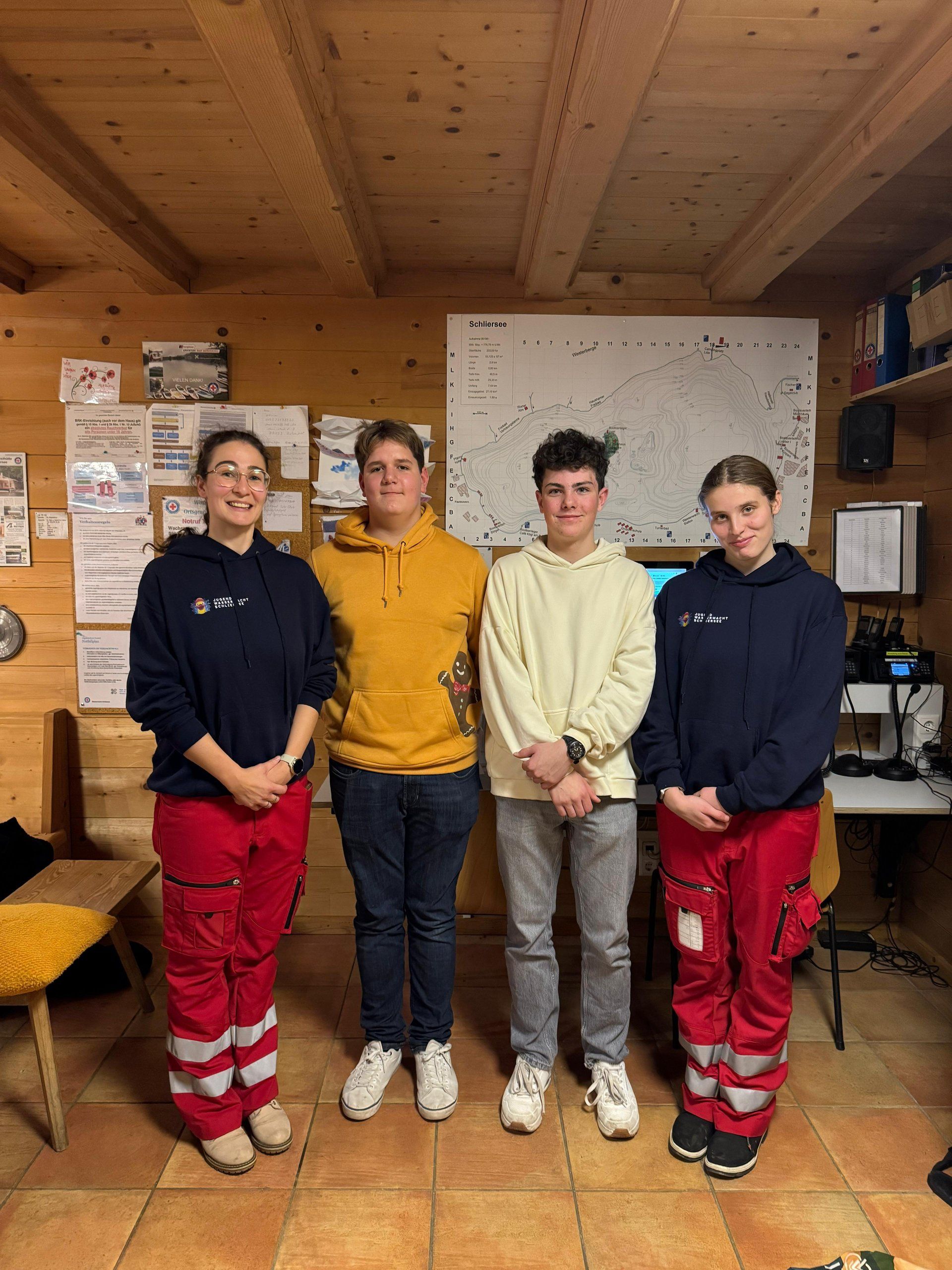 Neugewählte Stellvertretende Jugendleitung Hanna Zlotek und die beiden neuen Gruppenleiter posieren mit der Jugendleiterin vor dem Funkpult in der Wachstation der Wasserwacht Schliersee