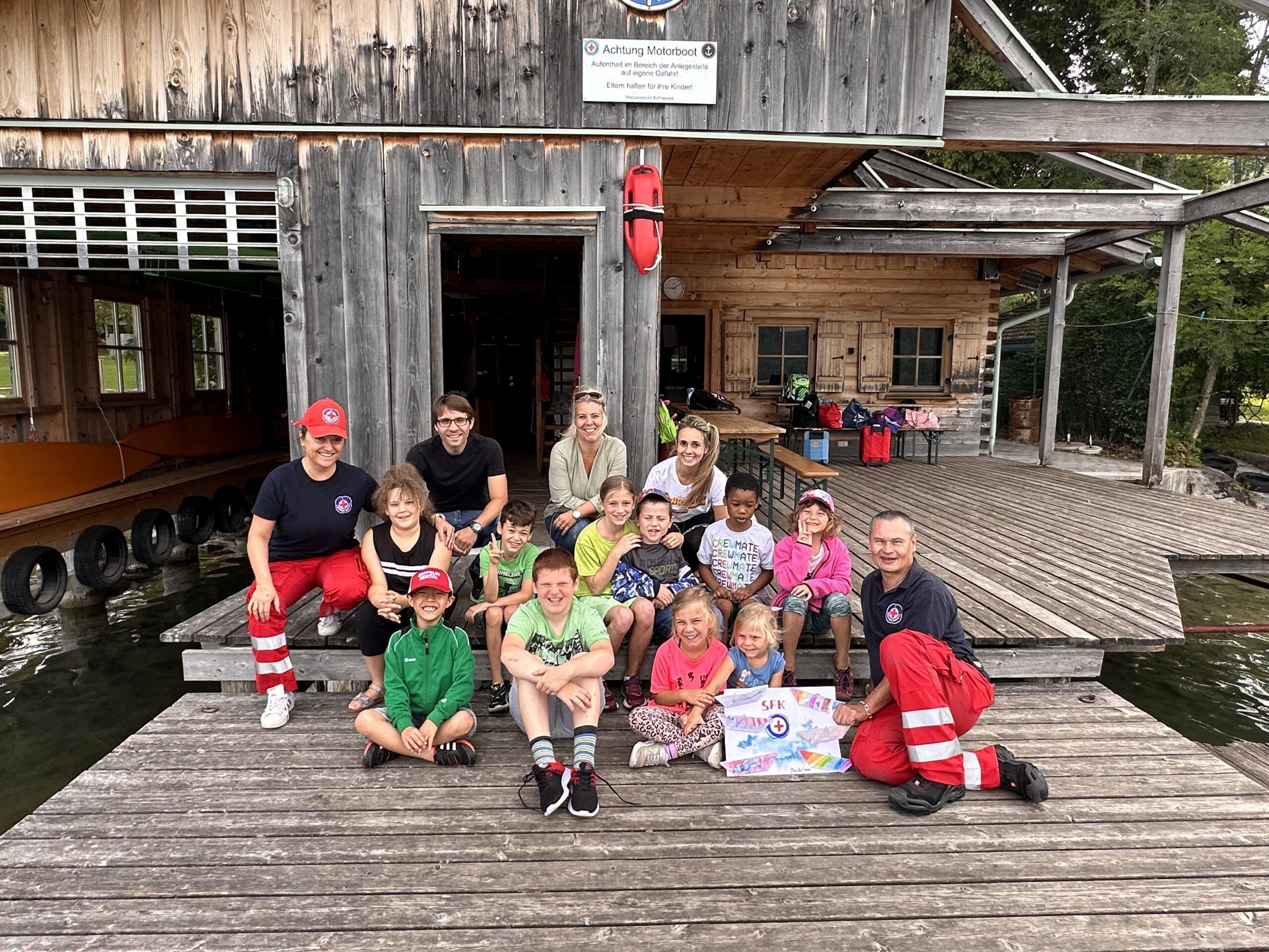 Schüler besuchten Wasserwacht Schliersee und sitzen am Steg für ein Gruppenfoto