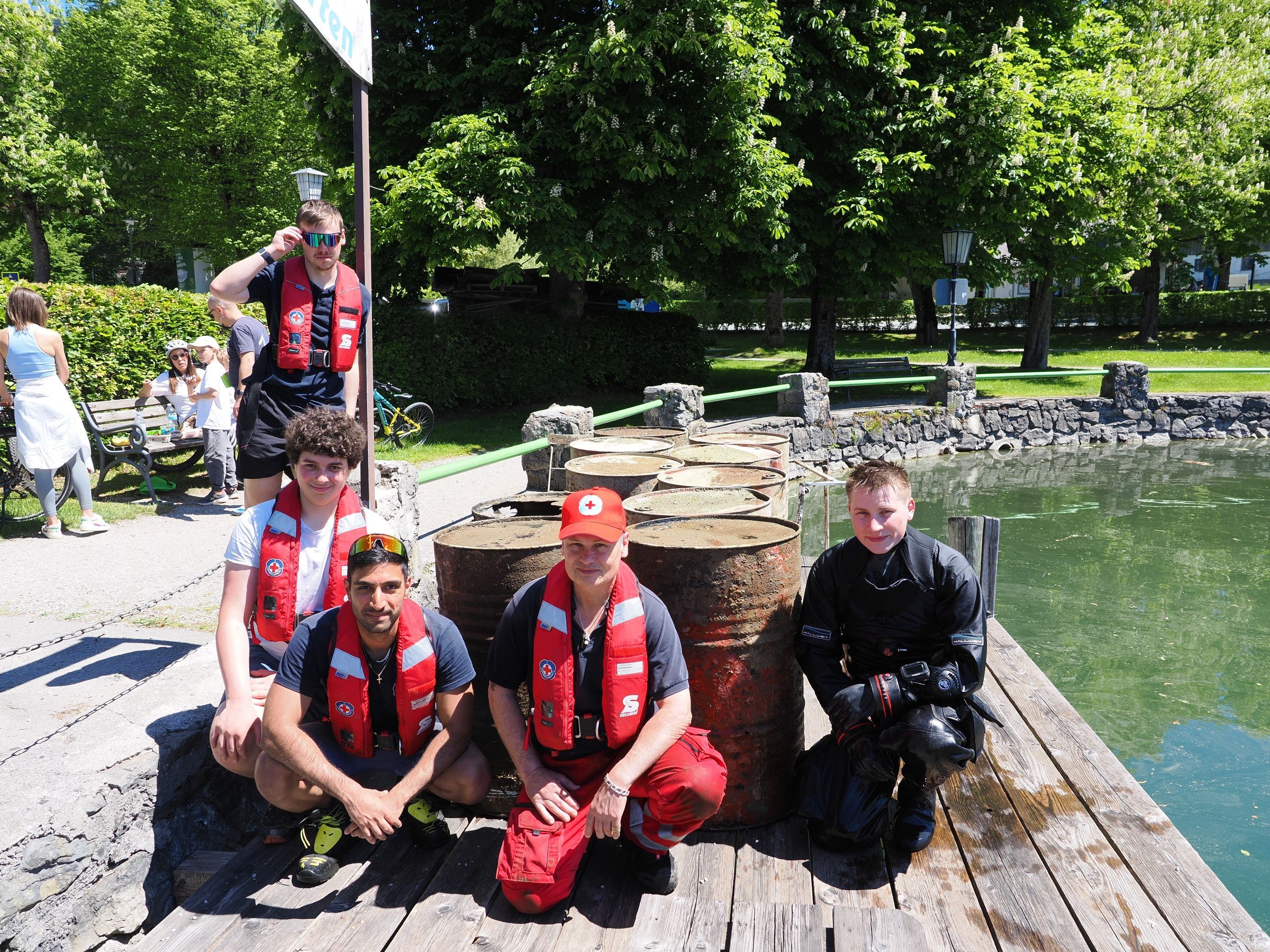 Rettungsraucher, drei Wasserretter und ein Jugendmitglied posieren nach erfolgreichem Arbeitseinsatz mit den geborgenen Fässern